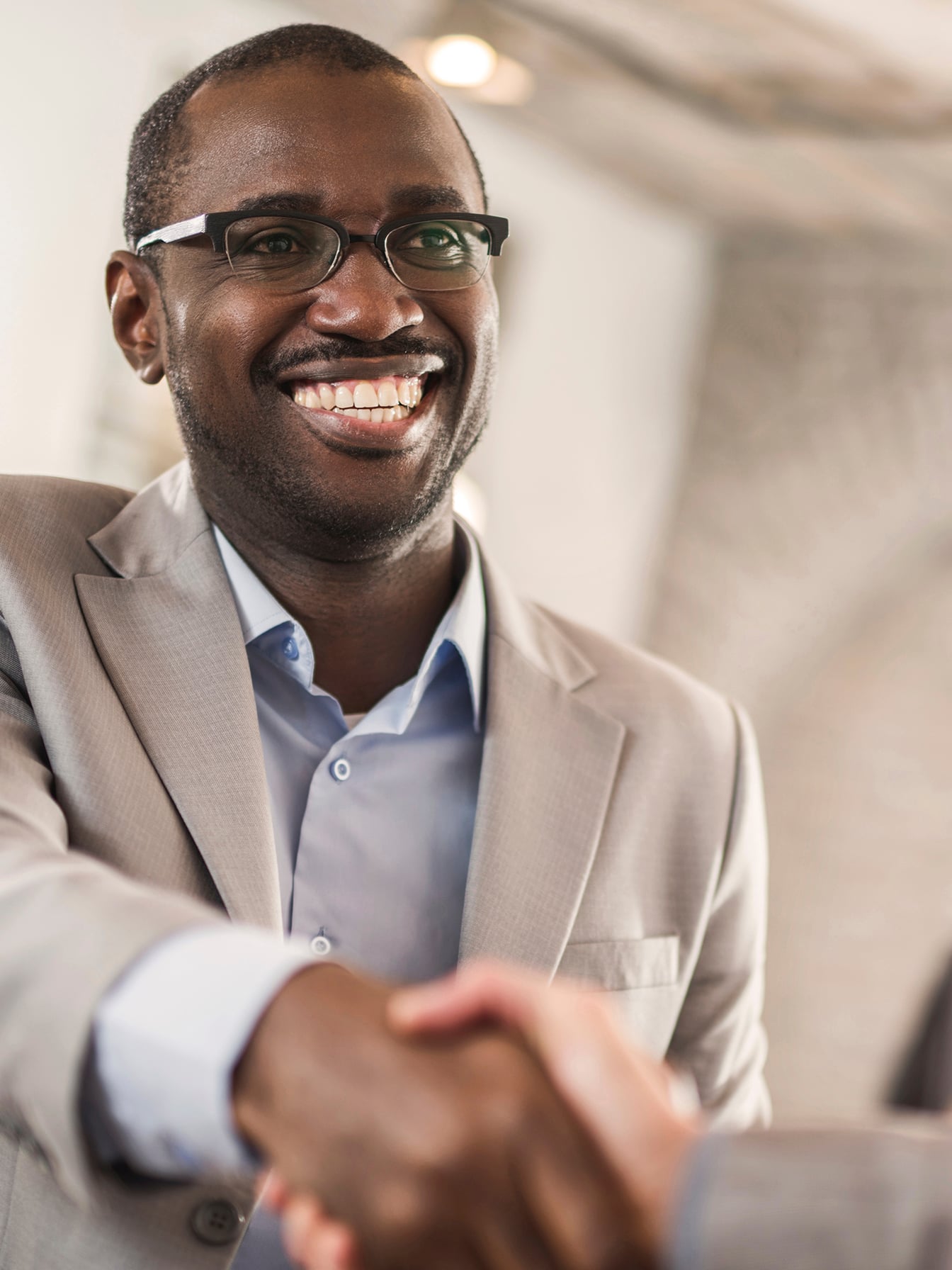 Happy African American businessman shaking hands with his unrecognizable colleague.